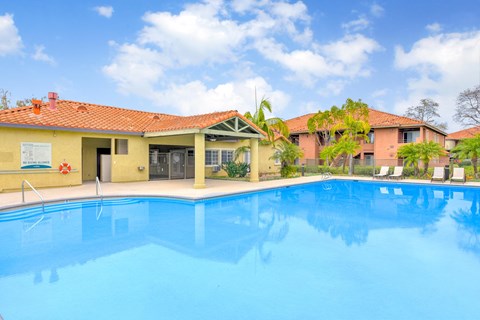 A swimming pool in front of a building with a red roof.
