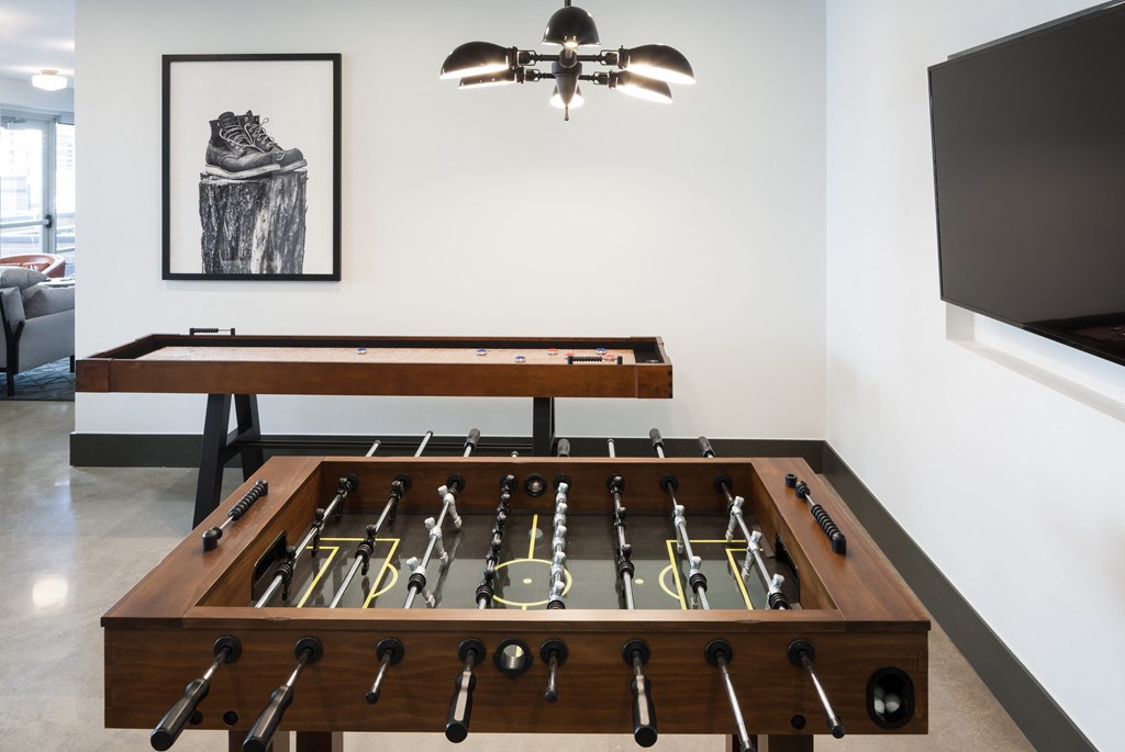 a foosball table sits in the center of a room with a tv on the wall