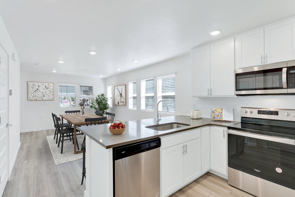 a kitchen with white cabinets and stainless steel appliances and a dining room table