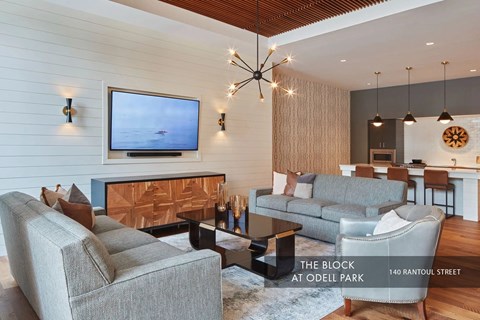 A modern living room with a grey couch and a flat screen TV mounted on the wall.