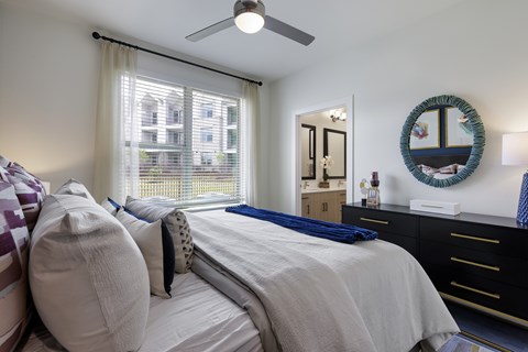 A bedroom with a large bed, a window with curtains, and a mirror on the wall.