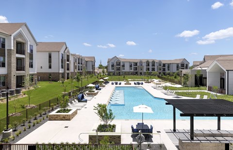 A pool surrounded by a black fence and a building in the background.