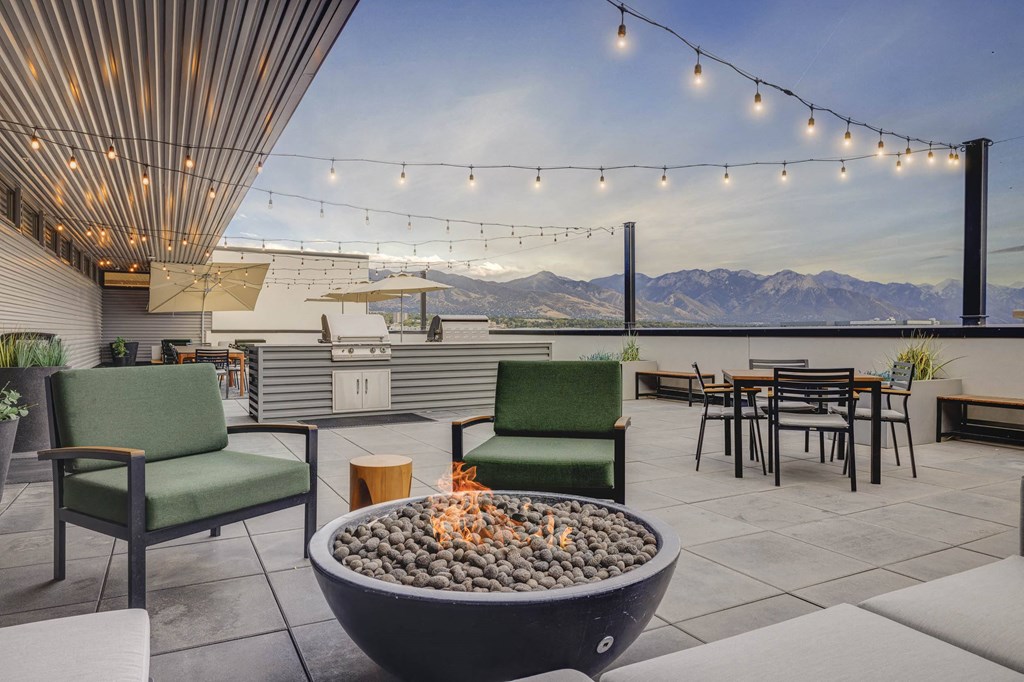 a patio with a fire pit and tables and chairs with mountains in the background