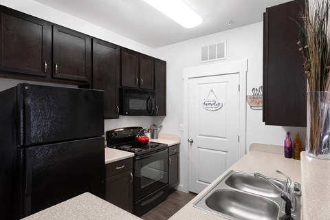 a kitchen with black appliances and a stainless steel sink