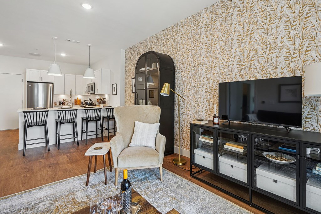 a living room with a television and a kitchen with a table and chairs