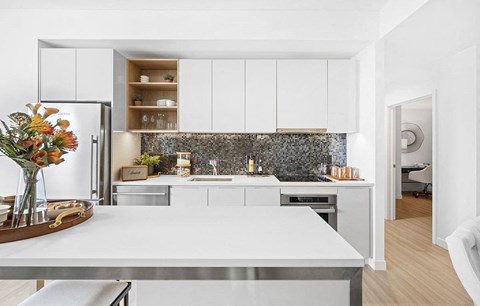 A modern kitchen with a white table and a marble backsplash.