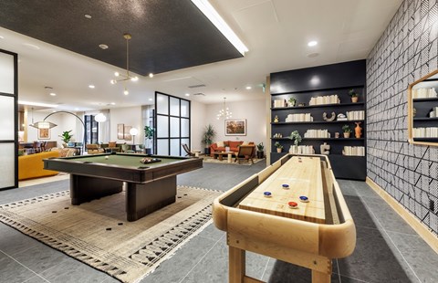 A room with a pool table and a shelf with various items on it.