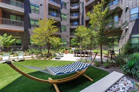 A hammock is strung between two trees in a courtyard.