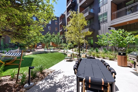 A long black table is surrounded by chairs in a courtyard.