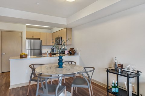 a dining area with a round table and chairs and a kitchen with a counter and