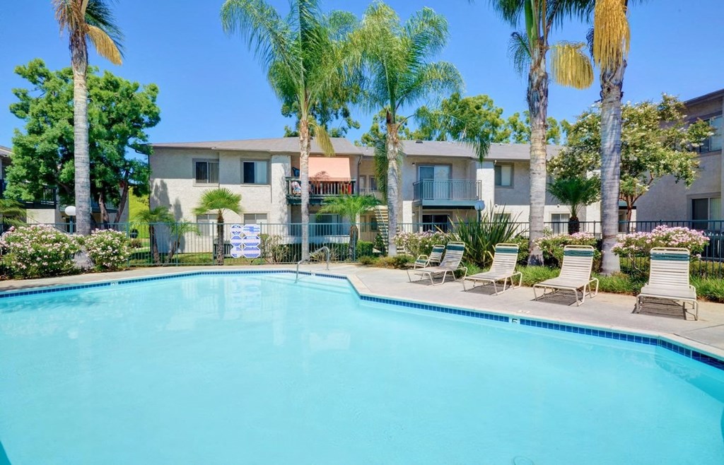 a swimming pool with palm trees and a building in the background