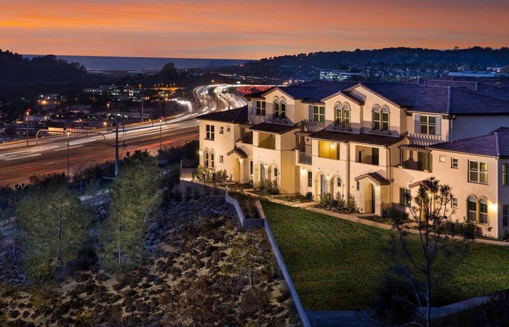 a house on a hill overlooking a city at sunset