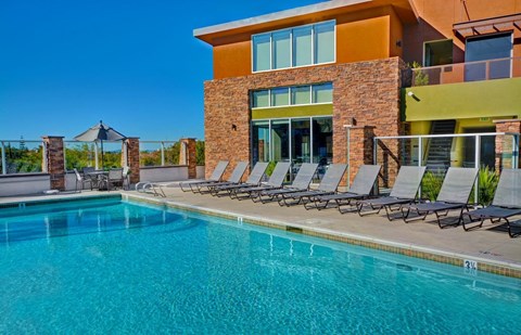 the pool area of a resort style swimming pool with lounge chairs