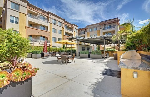 a patio with tables and umbrellas in front of apartments