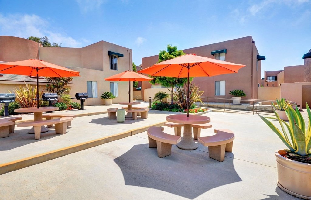 a patio with tables and umbrellas in front of a building