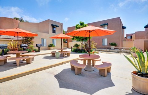 a patio with tables and umbrellas in front of a building