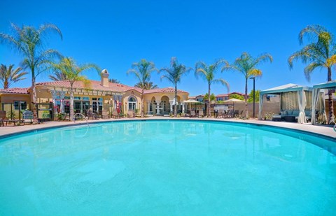 a large swimming pool in front of a hotel with palm trees