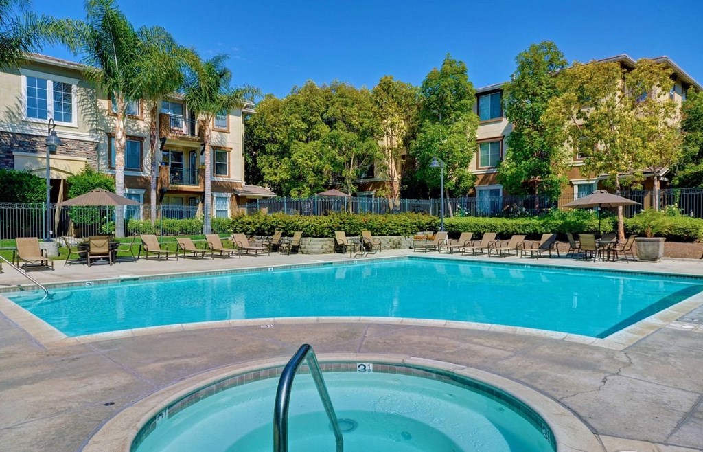 a swimming pool with chairs around it in front of an apartment building