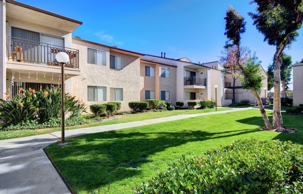 an apartment building with a sidewalk and lawn in front of it