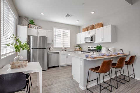 a kitchen with a bar and a stainless steel refrigerator
