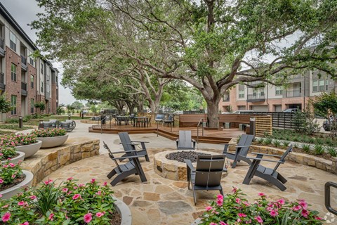 A patio with a table surrounded by chairs and flowers.