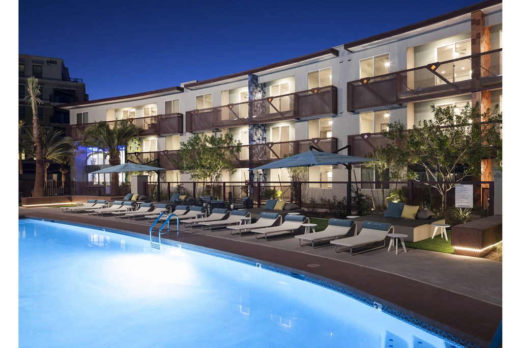 A swimming pool in front of a hotel at night.