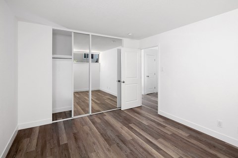 a bedroom with white walls and a hardwood floor