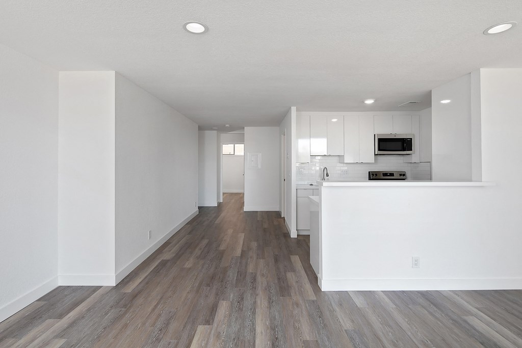 a bedroom with a medium sized bed and a kitchen with white cabinets