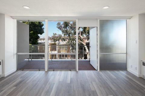 a living room with hardwood floors and glass doors leading to a balcony