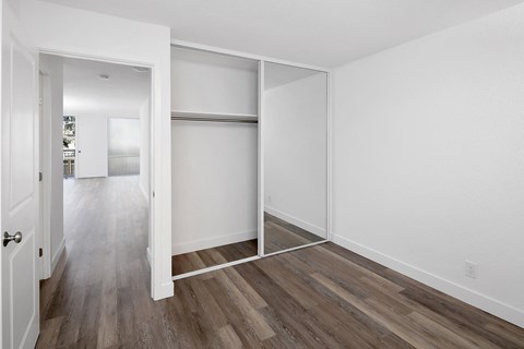 a bedroom with hardwood floors and white walls