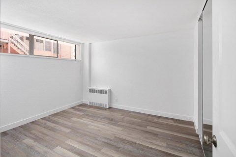 a bedroom with hardwood floors and white walls