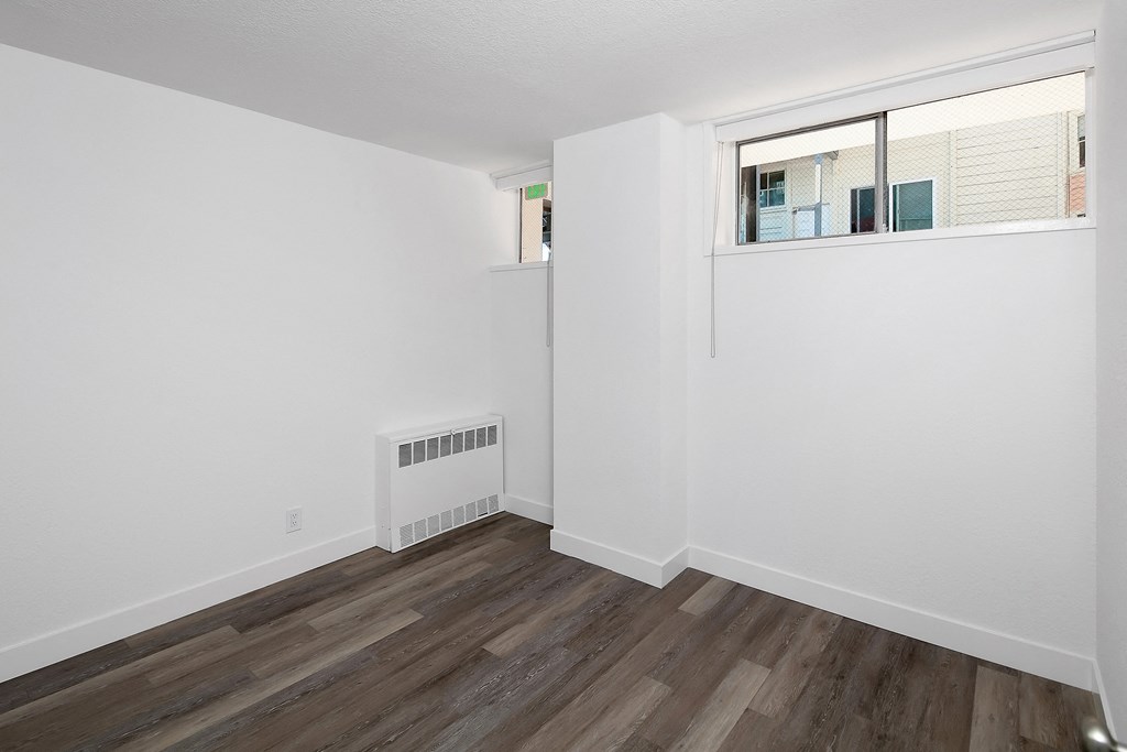 a bedroom with hardwood floors and white walls