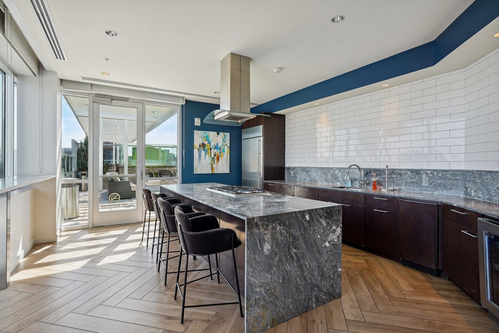 a kitchen with a long island with black chairs and a white and blue wall