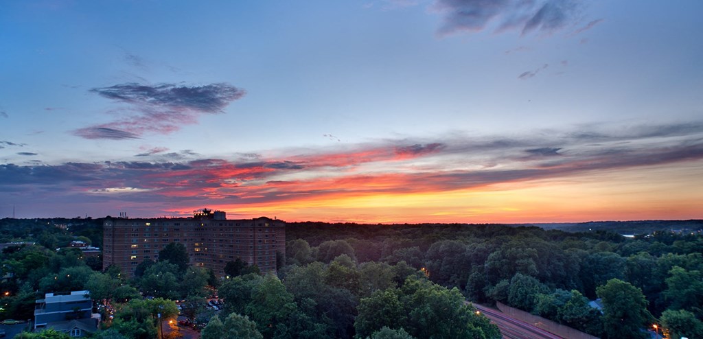 a sunset over a city with trees and a highway