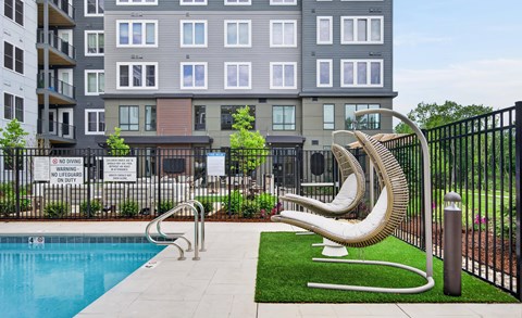 A pool surrounded by a black fence with a sculpture in front of it.