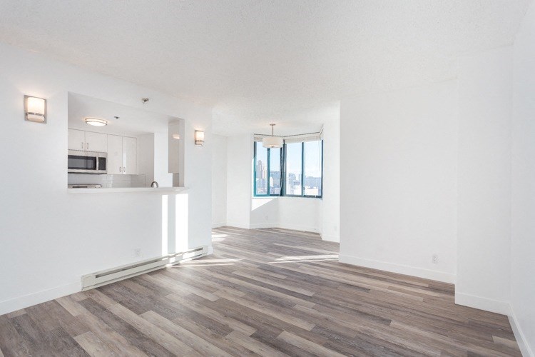 an empty living room with a kitchen in the background