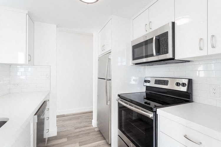 a kitchen with white cabinets and stainless steel appliances