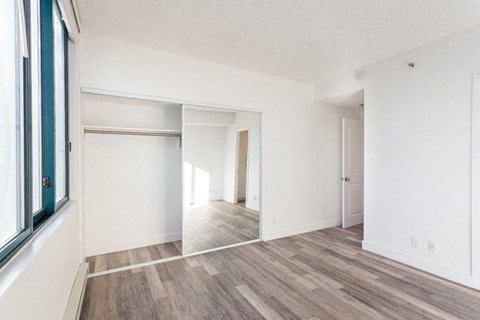 the living room and dining room of an apartment with wood flooring and a window