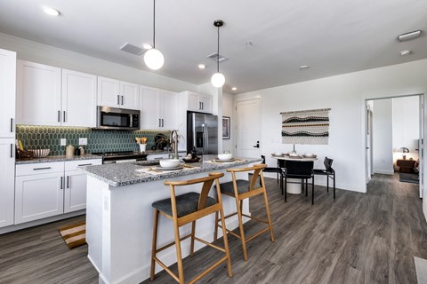 an open kitchen and dining area with a marble counter top and stools