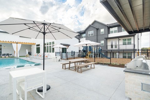 A patio with a table and chairs and a pool.