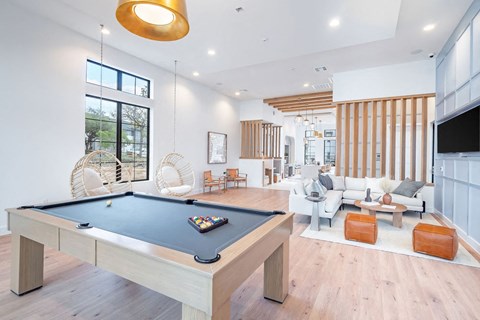 A billiard table is in the middle of a spacious room with a television and a couch.