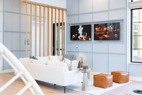 A living room with a white couch and a television on the wall.