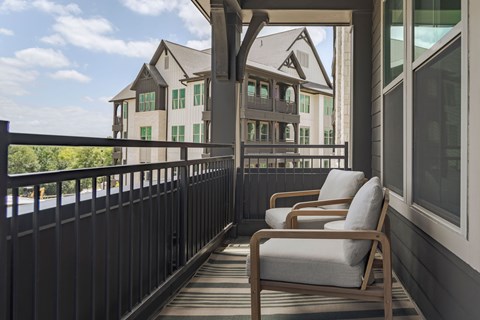 Two chairs on a balcony with a building in the background.