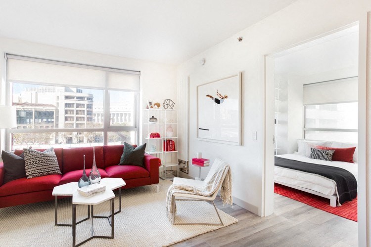 Dog Friendly Apartments in San Francisco CA - Trinity Place at 33 8th - Living Room with White, Red, and Pink Decor, a Large Window, a TV, Wall Art, Furniture, High Ceilings and Carpet