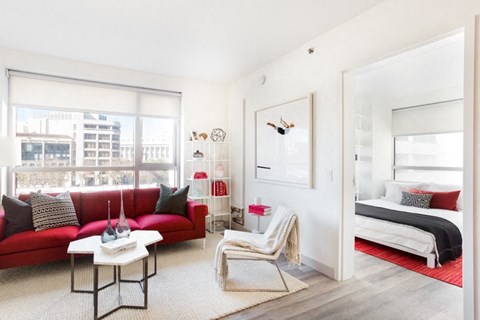 Dog Friendly Apartments in San Francisco CA - Trinity Place at 33 8th - Living Room with White, Red, and Pink Decor, a Large Window, a TV, Wall Art, Furniture, High Ceilings and Carpet