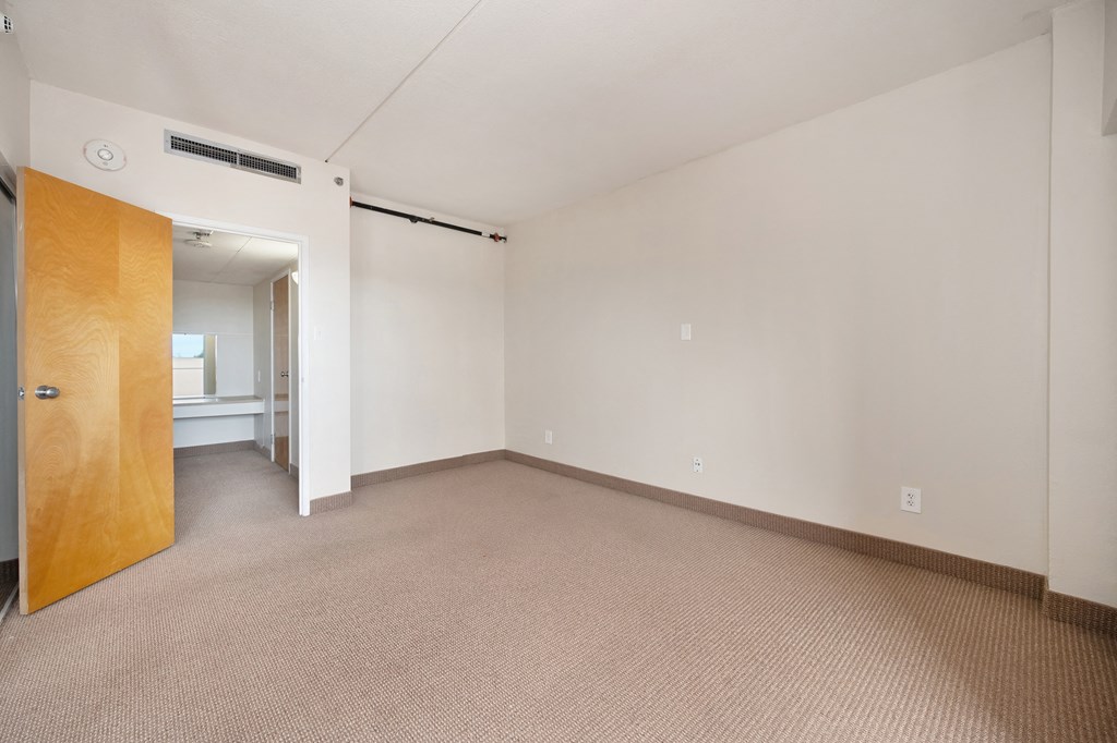 an empty living room with a door to a bathroom