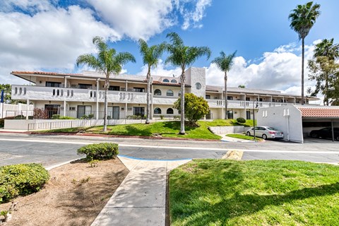 A building with a white fence and a car parked in front.