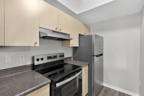 A kitchen with a black stove top oven and a stainless steel refrigerator.