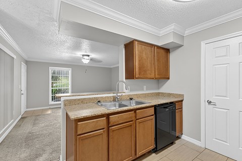 A kitchen with wooden cabinets and a black dishwasher.