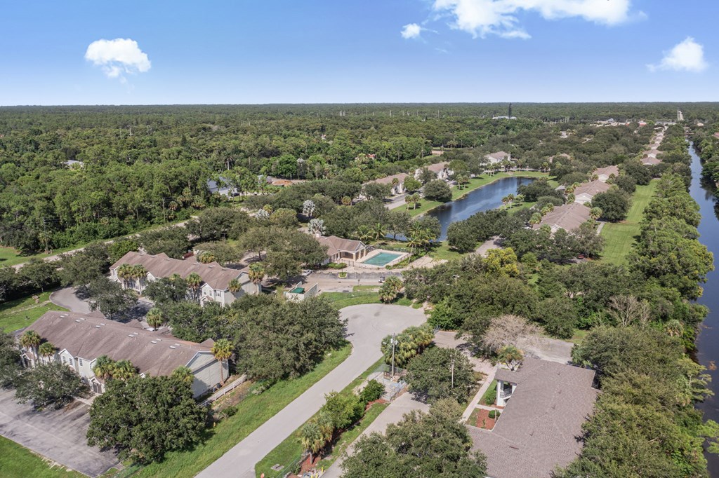A bird's eye view of a residential area with houses, trees, and a river.